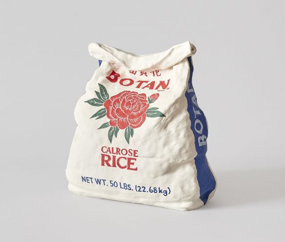 white background wiht a large rice bag ceramic sculpture in the middle, a white bag with a red rose in the center with green stems, and red text at top and bottom