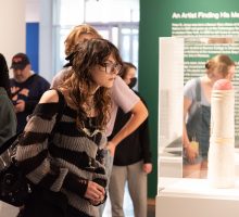 People in a museum looking at artwork in a case.