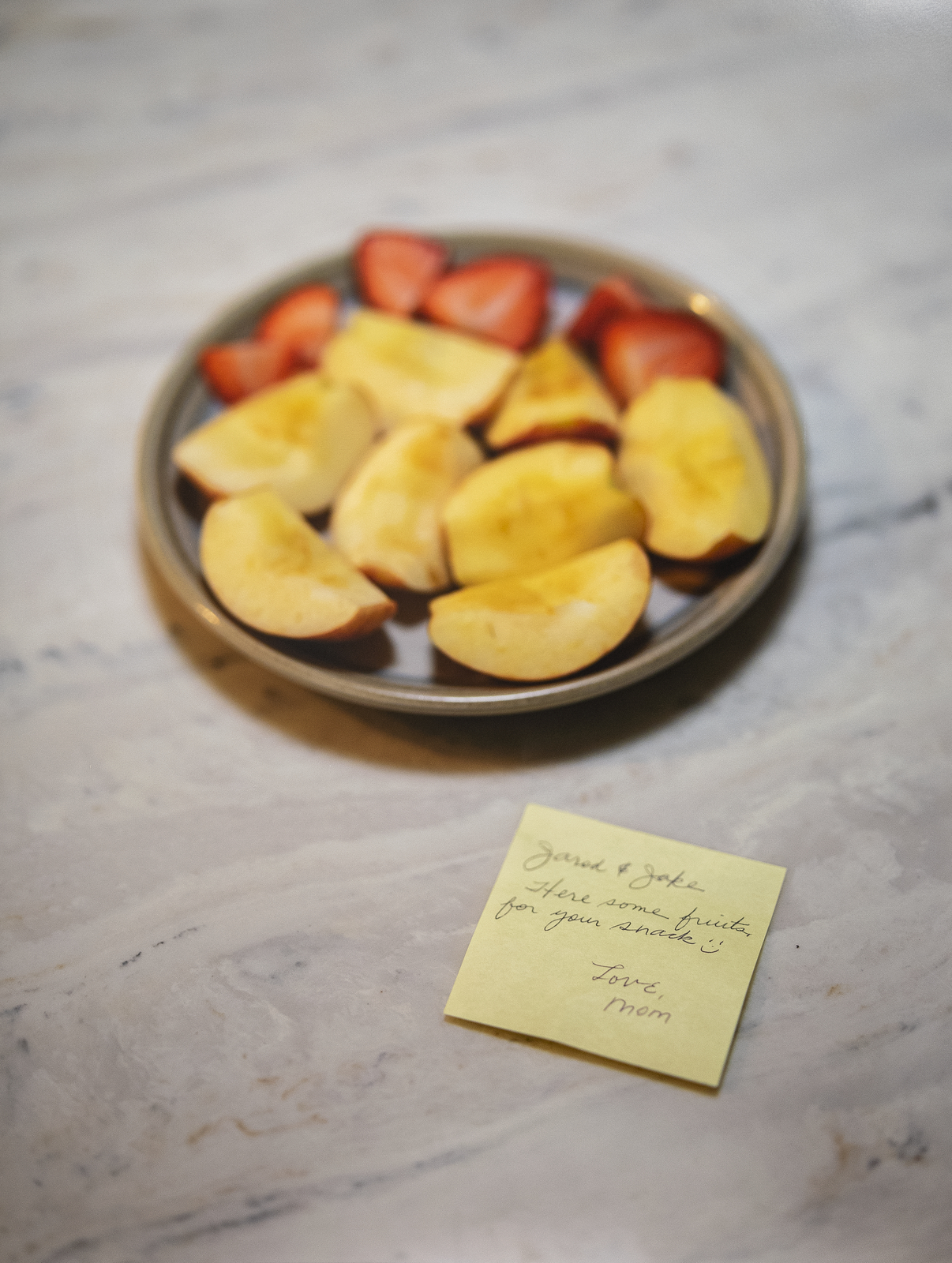A photography by Jarod Lew depicting a plate of cut fruits and a post-it note.